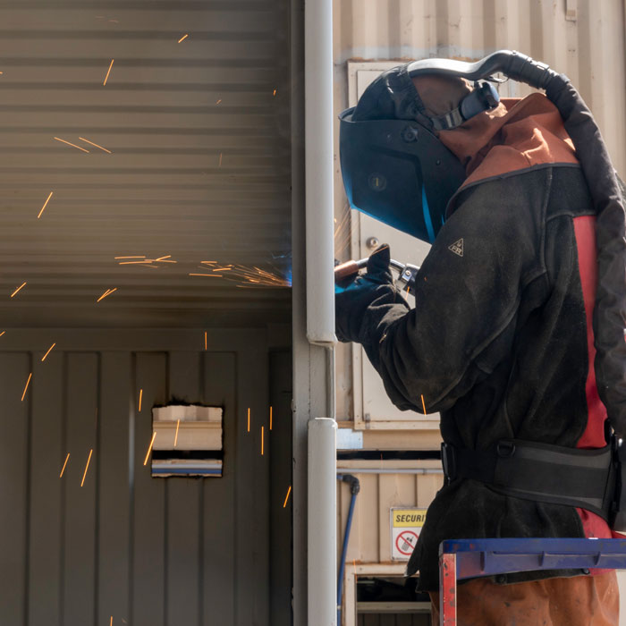 SCF worker welding a modified container